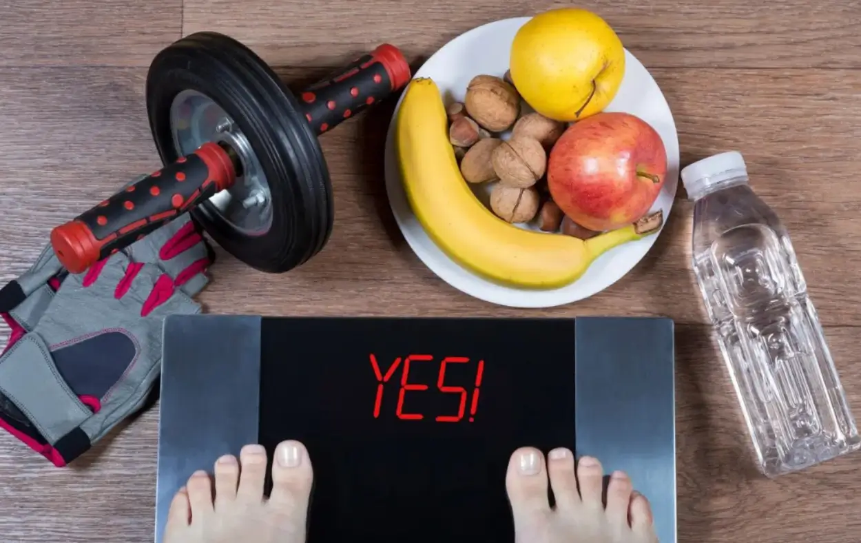 A person standing on their scale with an apple, banana and nuts.