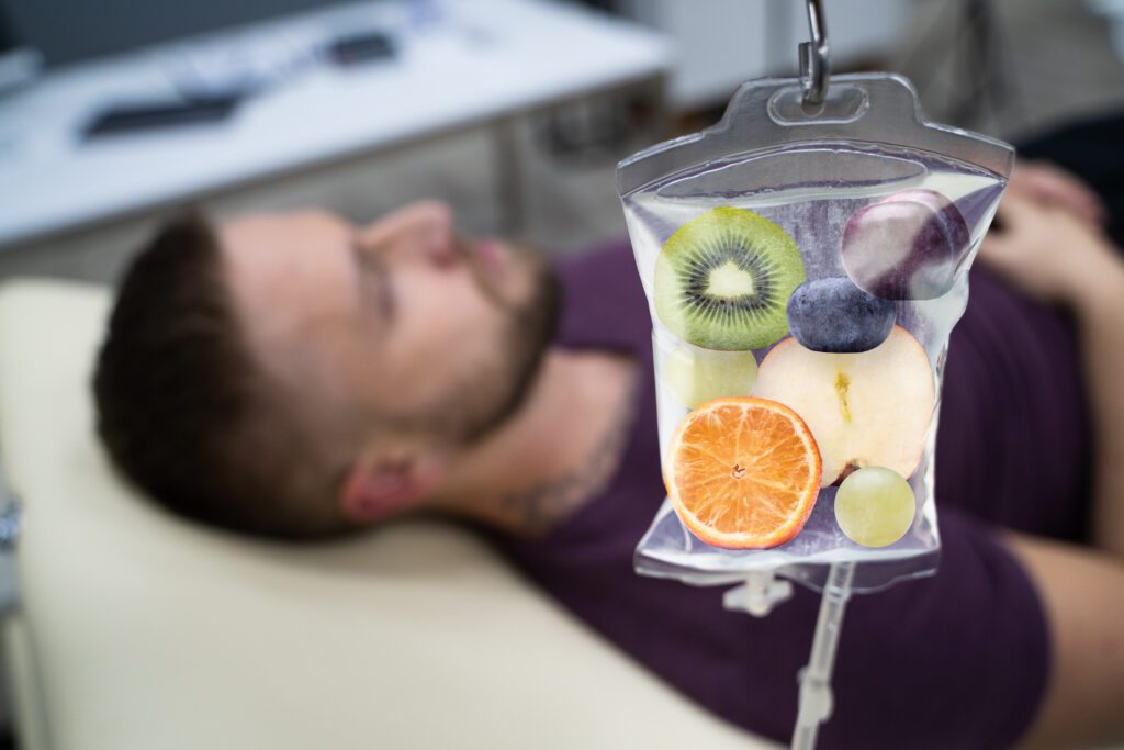 A man laying in bed with an iv bag filled with fruit.