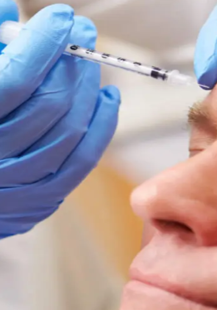 A person with blue gloves is getting their face shot