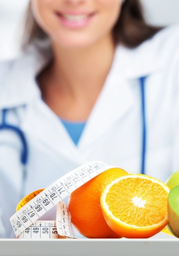 A doctor sitting at the table with fruits and an apple.